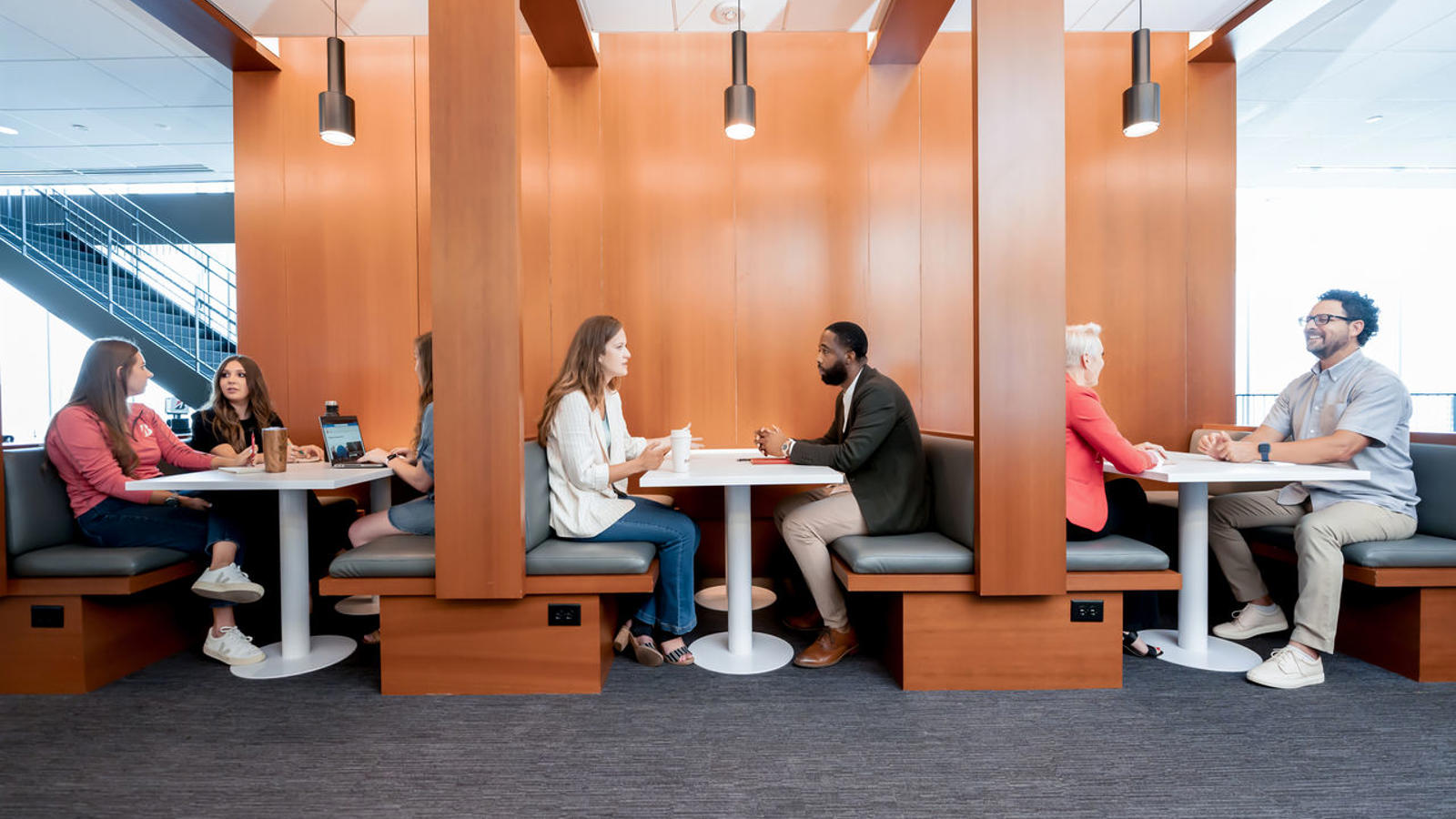 a group of people sitting at tables in a room with wood walls