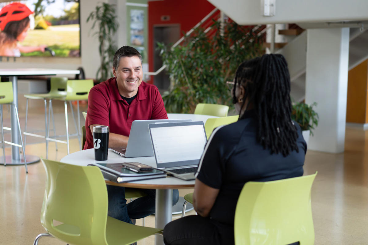 a man and woman sitting at a table with laptops