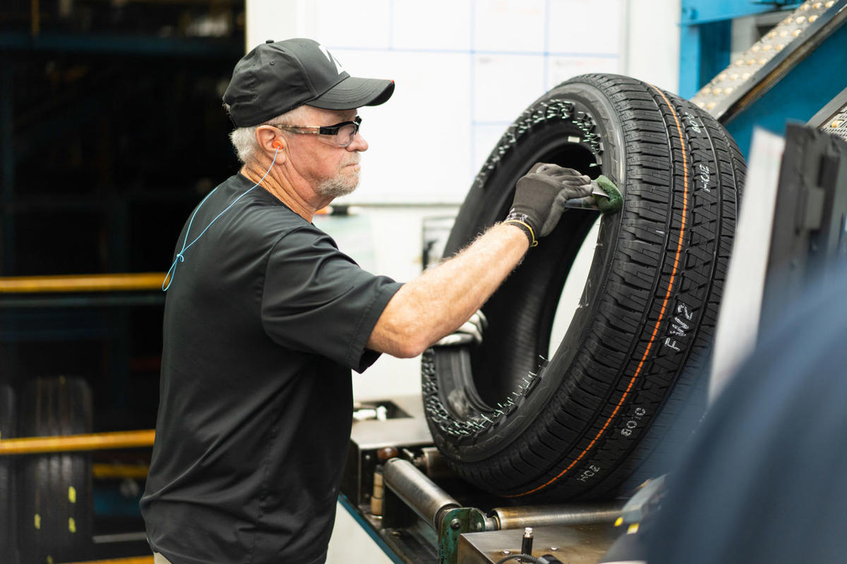 a man wearing a hat and gloves working on a tire