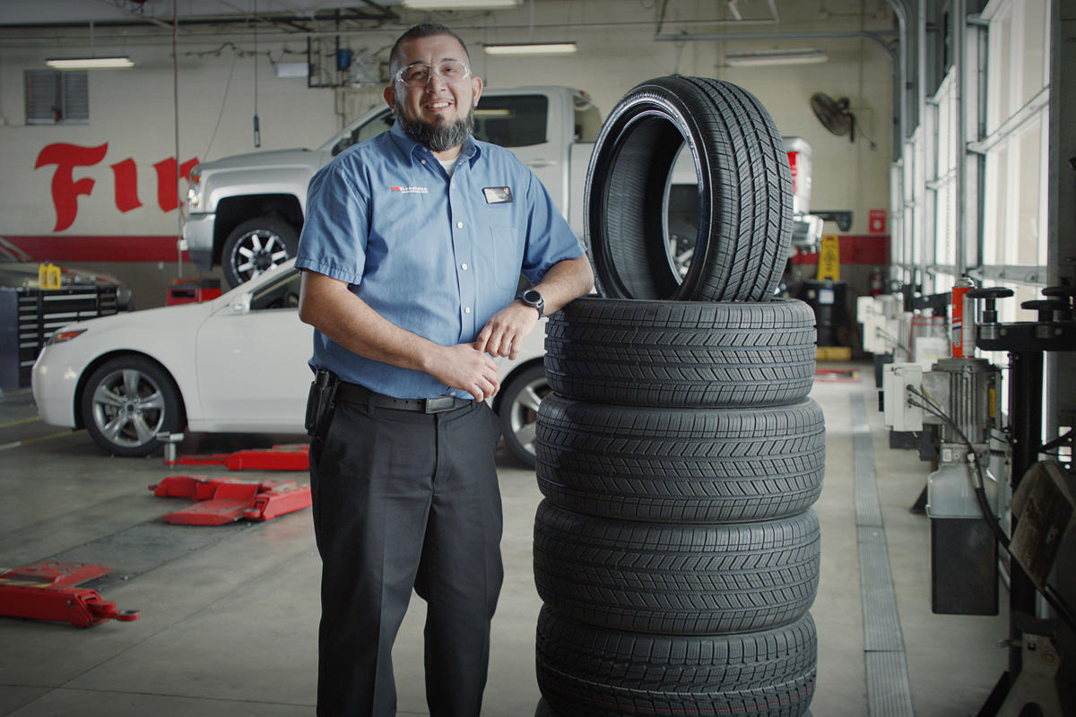 a man standing next to a stack of tires